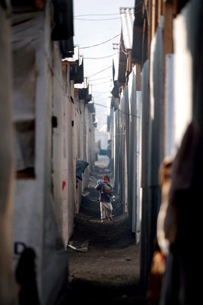 Mladá guatemalská dívka, již rodina je po loňském neštěstí bez domova, nese svou sestřičku mezi domy v dočasném táboře v městečku Panabaj. | Foto: Reuters