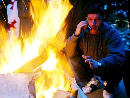 Obyvatel Tbilisi se na ulici zahřívá u provizorního táboráku. | Foto: Reuters