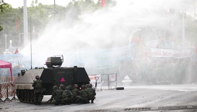 Obrněné transportéry dnes ráno po výzvě povstalcům k bezodkladnému vyklizení tábora prorazily hořící barikády z pneumatik, bambusu a ostnatého drátu, které obklopovaly obsazenou zónu. | Foto: Reuters