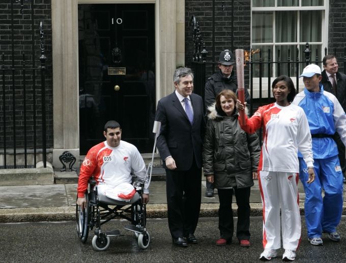 Britský premiér Grodon Brown (druhž zleva) vítá atletku Denise Lewisovou, která k němu s pochodní dorazila. Kromě něj ji vítá i ministryně pro olympiádu Tessa Jowellová a handicapovaný sportovec Ali Jawad. Ten od ní pochodeň převzal. | Foto: Reuters