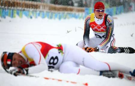 Vyčerpaný bronzový Tobias Angerer (vzadu) v cíli běhu na 15 km klasicky. Vpředu leží Francouz Vincent Vittoz | Foto: Reuters