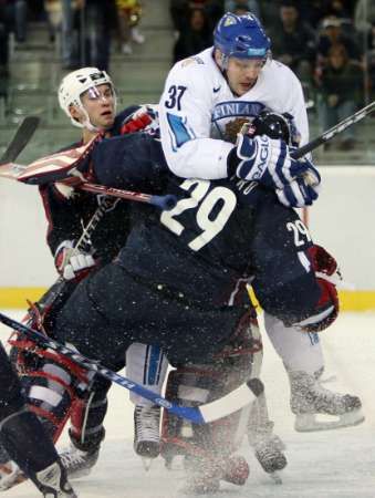 Jarkko Ruutu z Finska (v bílém) atakuje gólmana USA Ricka Dipietra. Vlevo je obránce Brian Rafalski. | Foto: Reuters