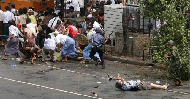 Zraněný muž s fotoaparátem se nedokáže zvednout. Přichází vojáci se samopaly. Dav prchá. | Foto: Reuters