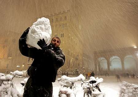 Husté sněžení zasáhlo také Itálii. Muž odnáší sněhovou kouli z náměstí Piazza della Signoria ve Florencii. | Foto: Reuters