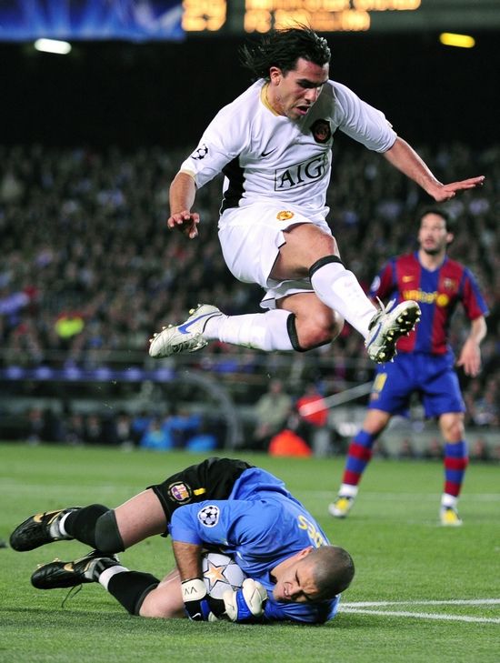 Carlos Tevez z Manchesteru přeskakuje v semifinále Ligy mistrů barcelonského gólmana Valdese. | Foto: Reuters