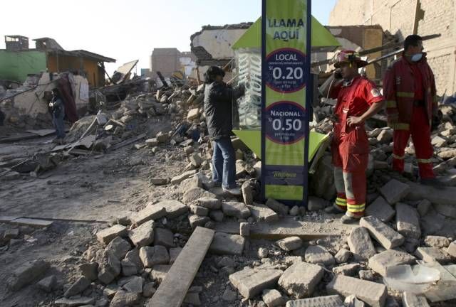 Záchranáři i místní se pokouší dovolat z veřejné budky. Zemětřesení v Peru zle poškodilo i místní telekomunikace. | Foto: Reuters