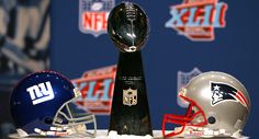 O trofej Vince Lombardiho pro vítěze NFL se ve 42.Superbowlu utkají týmy New York Giants (helma vlevo) a New England Patriots | Foto: NFL