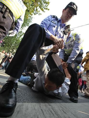 Policemen tackle a demonstrator on the ground during a protest near the Japanese consulate on the 81st anniversary of Japan's invasion of China, in Shanghai September 18, 2012. Anti-Japan protests reignited across China on Tuesday, forcing Japanese firms in the country to suspend operations, as a crisis over a territorial dispute escalated on the day Chinese commemorated Japan's 1931 occupation of its giant neighbour. REUTERS/Aly Song (CHINA - Tags: POLITICS CIVIL UNREST TPX IMAGES OF THE DAY | Foto: Reuters