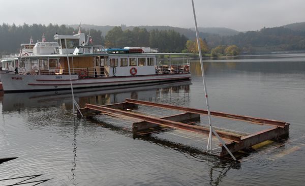 Vytáhnout téměř třicetitunovou loď na břeh není hračka. Plavidlo si najede nad servisní vozík, který je předtím spuštěn pod hladinu. Loď se zajistí zarážkami a vytáhne z vody. Poté následuje omytí spodku od řas a usazenin a odtažení do doků | Foto: Attila Racek