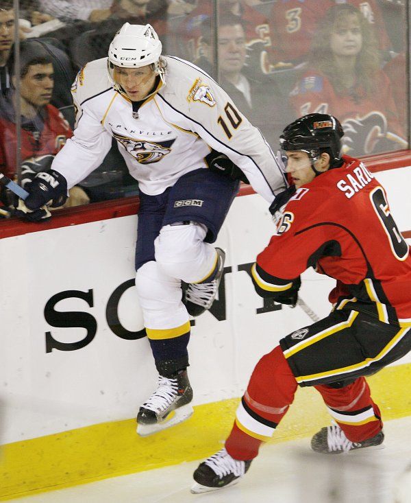 Martin Erat z Nashville Predators se snaží přeskočit hůl Coryho Saricha z Calgary Flames. | Foto: Sport, Reuters