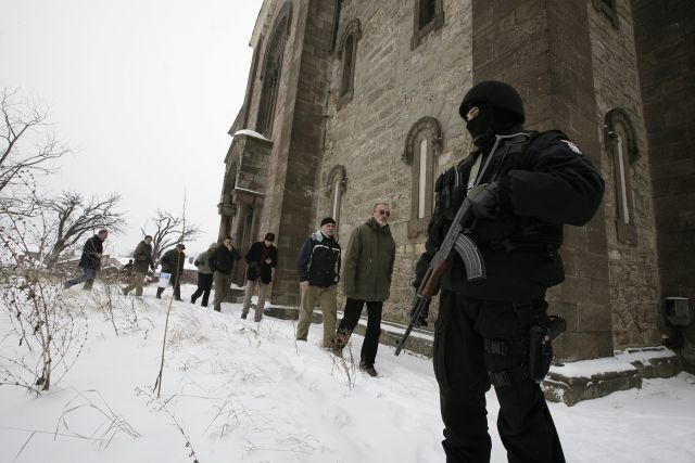 Polský příslušník mezinárodních mírových sil střeží srbský pravoslavný kostel v albánské části Kosovské Mitrovice. V roce 2004 byl skupinou kosovských Albánců zapálen a poničen. | Foto: Reuters