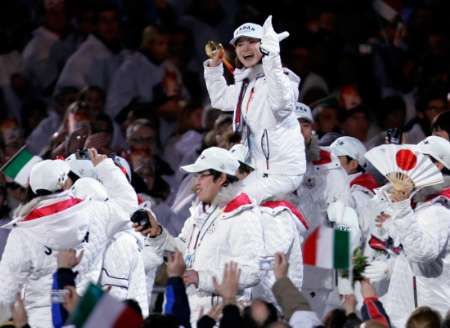 Japonská krasobruslařka Šizuka Arakawová při závěrečném ceremoniálu na ramenou jiného člena výpravy ukazuje svou zlatou medaili. | Foto: Reuters