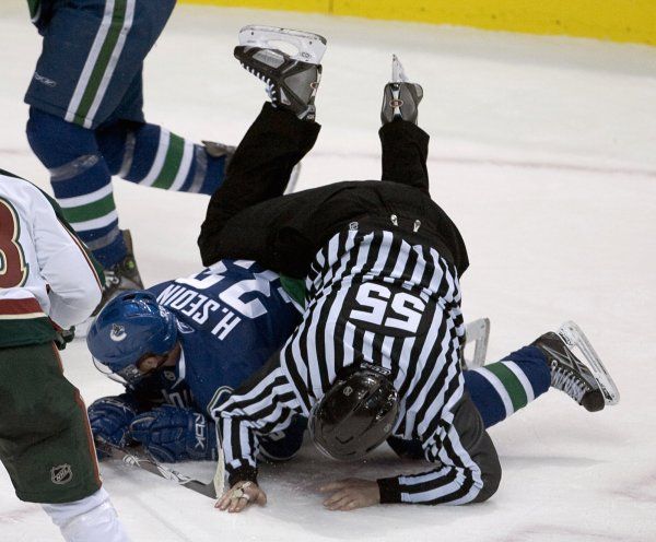 Rozhodčí padá přes Henrika Sedina z Vancouveru Canucks. | Foto: Reuters