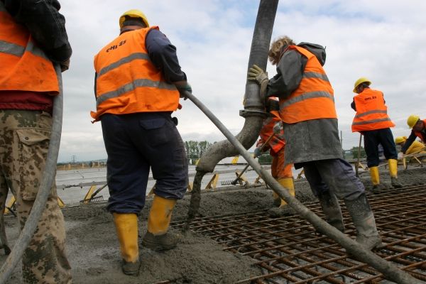 Ty menší hadice jsou vibrátory, které beton vhánějí mezi armaturu a vytláčejí z něj vzduch. Ta "lavička" vzadu uhlazuje povrch do stanovené roviny. Když se zapne, zní to, jakoby vám za zády zahoukal vlak. | Foto: Karel Toman