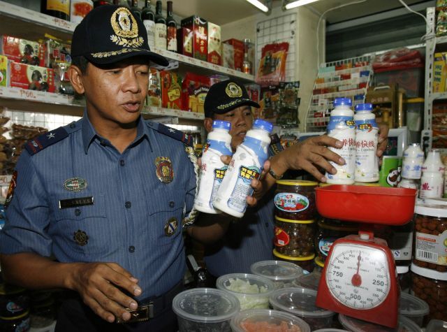 Policisté odstraňují čínské mléko z obchodu ve filipínské Manile. | Foto: Martin Novák, Reuters