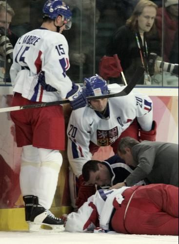 Tomáš Kaberle (vlevo) a Robert Lang se spolu s lékařem a masérem sklánějí nad zraněným Jaromírem Jágrem v Turíně 2006. | Foto: ČTK/AP