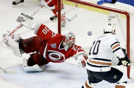 Gólman Caroliny Hurricanes Cam Ward při zákroku proti Shawnu Horcoffovi z Edmonton Oilers ve finále Stanley Cupu. | Foto: Reuters