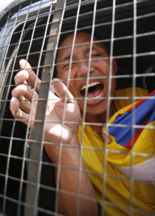 Tibetská protestující křičí po zatčení z policejní dodávky. | Foto: Reuters