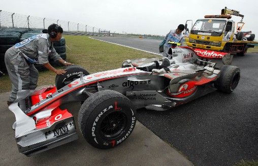 Pracovníci okruhu v Šanghaji se připravují na odtažení McLarenu Lewise Hamiltona, který skončil v kačírku v příjezdu do boxů. | Foto: Reuters