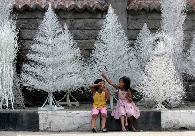 Já sním o Vánocích bílých... v podání dětí před prodejnou stromků ve filipínské Manile. | Foto: Reuters