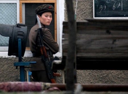 Severokorejská vojákyně hlídkuje ve městě Sinujiu na severokorejské straně řeky Ja-lu, která odděluje Severní Koreu od Číny | Foto: REUTERS / Reinhard Krause