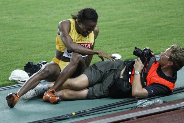 S prstem na spoušti a atletkou na zádech. Maria Mutolaová padá přes fotografa, číhajícího na dobrý záběr. | Foto: Reuters