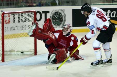 Mike Comrie z Kanady (v bílém) skóruje za záda dánského gólmana Petera Hirsche. | Foto: Reuters