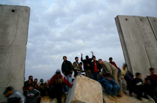 Palestinci stojí u barikády na hranici pásma Gazy s Egyptem poté, co ji palestinští ozbrojenci rozbořili. Středa 4. ledna 2005. | Foto: Reuters/Ibrahím Abú Mustafa