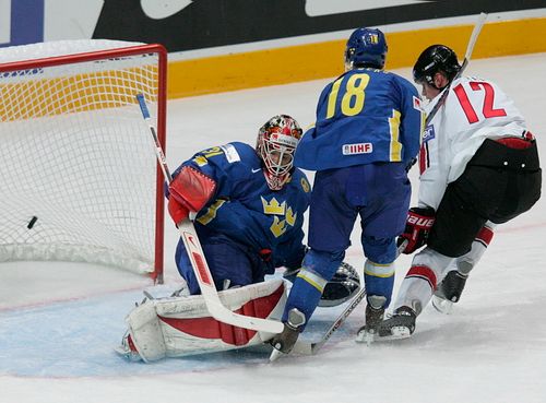 Kanaďan Eric Staal (v bílém) sköruje do sítě švédského gólmana Johana Backlunda. Nezabránil mu v tom ani Per Hallberg (18). | Foto: Reuters