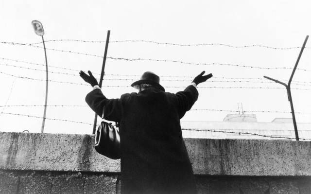 Tato žena čekala na západní straně zdi přes tři hodiny, aby spatřila své příbuzné na východoněmecké straně zdi. Fotografie z roku 1961. | Foto: Wikimedia Commons