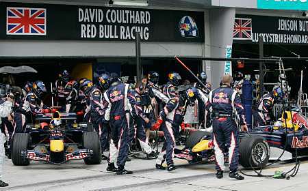 Mechanici týmu Red Bull tlačí monopost Davida Coultharda (vlevo) do boxů, zatímco Christian Klien tankuje a mění pneumatiky | Foto: Reuters