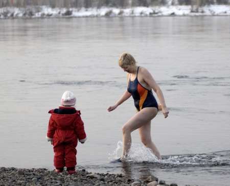 Matka s dítětem v sibiřském městě Krasnojarsk využívá nezvykle teplé zimy a koupe se v Jeniseji | Foto: Reuters