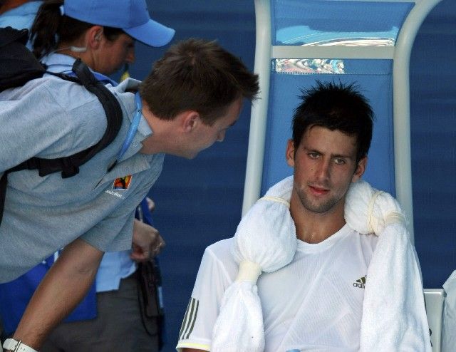 Zlomený Novak Djokovič se radí během lékařské přestávky se svým trenérem. | Foto: Reuters