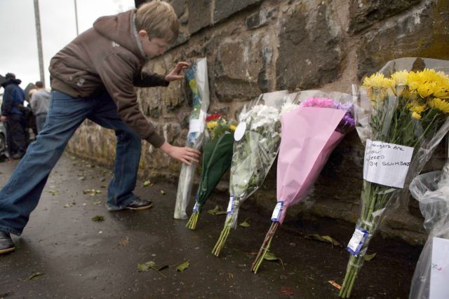 Na místo, kde byli v sobotu večer zastřeleni dva vojáci, nosí lidé květiny. | Foto: Reuters