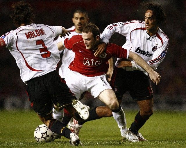 Hráči AC Milána Alessandro Nesta (vpravo) a Paolo Maldini (vlevo) se snaží odzbrojit Wayna Rooneyho z Manchesteru United v semifinále Ligy mistrů. | Foto: Reuters