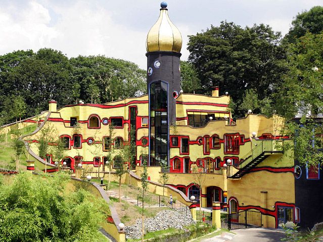 Hundertwasserhaus, Grugapark, Essen  Kromě turistického, rodinného a sportovního využití přináší Grugapark také ukázku architektury  Friedenstreicha Hundertwassera, věhlasného rakouského architekta. Na procházce essenským parkem se tak před vámi najednou vynoří v průhledu vysokých stromů pestrobarevná stavba rakouského architekta Hundertwassera. Nejde sice o technickou památku, ale pokud zmiňujeme tento park, rozhodně stojí za zmínku i takto unikátní stavba, která, jako ostatně všechna díla tohoto architekta, působí jakoby z jiné planety či ze světa Alenky v říši divů. | Foto: Grugapark