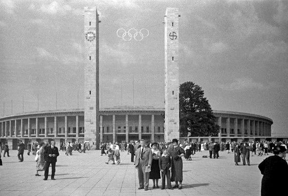 Olympijský stadion se vstupním portálem. Hodiny na levém sloupu přežily dodnes, svastika ne. | Foto: Wikimedia Commons - Hubicka - CC BY SA 3.0