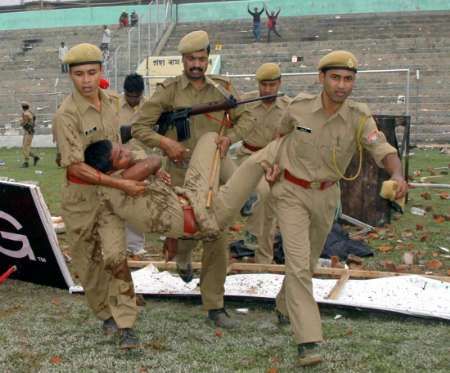 Policisté odnášejí zraněného kolegu při nepokojích, které vypukly po zrušení kriketového zápasu v indickém Guwahati. | Foto: Reuters