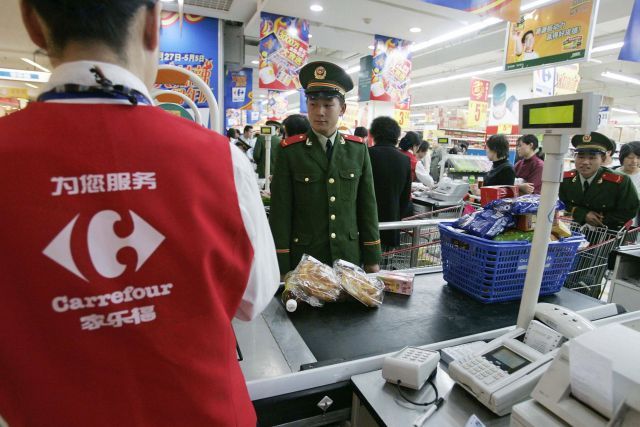 Příslušník čínské armády u pokladny Carrefouru v Šanghaji. | Foto: Reuters