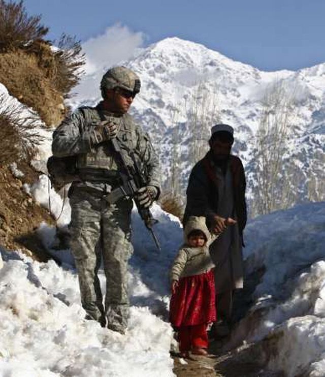 Afghánec s malou dcerkou prochází kolem hlídkujícího amerického vojáka v provincii Paktíja na jihovýchodě země. | Foto: Reuters