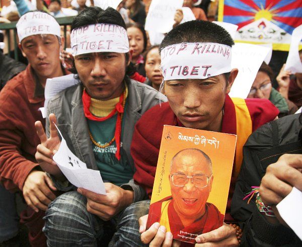 Tibetští demonstranti drží obrázek Dalajlámy. | Foto: Reuters