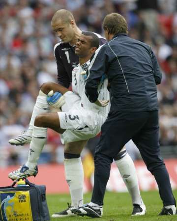 Zraněný nglický fotbalista Ashley Cole je odnášen za pomoci reprezentačního brankáře Paula Robinsona při utkání v Estonsku. | Foto: Reuters