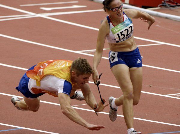 Vodič nevidomé britské atletky Tracey Hintonové padá za cílovou čárou. | Foto: Reuters