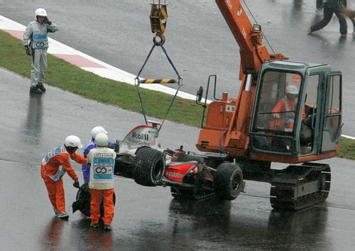 Pořadatelé odklízejí z trati ve Fudži rozbitý monopost McLaren Fernanda Alonsa. | Foto: Reuters