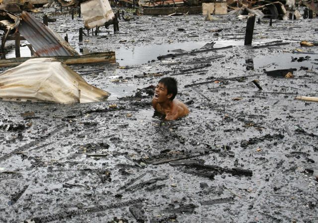 Filipínec se brodí vodou bahnem po sesuvech půdy na předměstí Manily. | Foto: Reuters