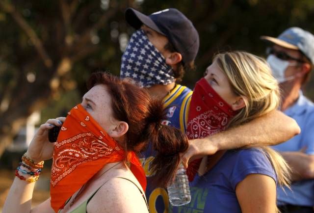 Vyděšené San Diego: (zleva doprava)Kaitlyn Terrillová, Joey Terrill a and Anna Ksenvenková pozorují, jak se jim nad hlavami vznáší helikoptéry a vodními vaky. | Foto: Reuters