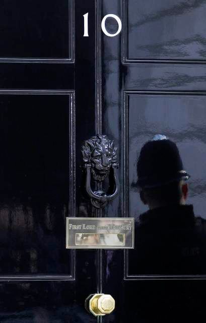 Čapka. Odraz typického britského policisty ("bobíka") ve dveřích Downing Street 10. | Foto: Reuters