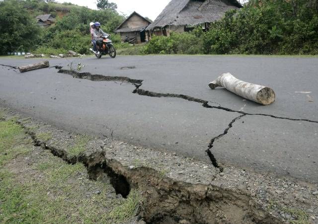 Motocykl projíždí po silnici silně poničené otřesy půdy. | Foto: Reuters