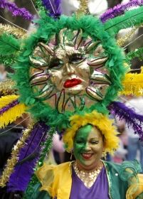 Fialová, zelená a zlatá jsou tradičními barvami neworleanského karnevalu. Do stejných barev se oblékla i členka skupiny (krewe) Iris | Foto: Reuters