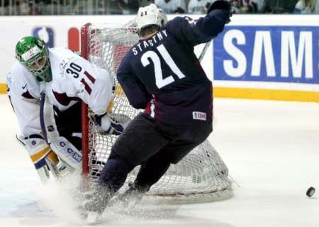 Yan Stastny z USA (v modrém) se snaží vyzrát na lotyšského gólmana Sergejse Naumovse. | Foto: Reuters